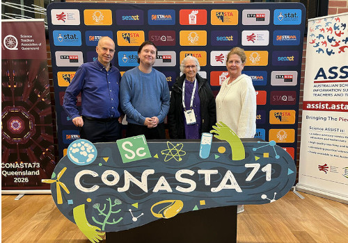 Four people standing behind a table at a conference